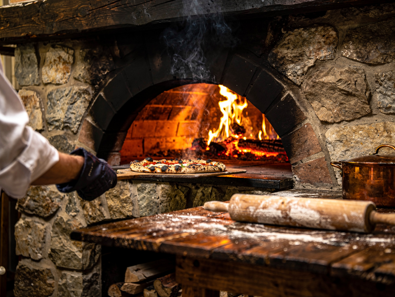 Chef preparing pizza in glowing wood-fired stone oven